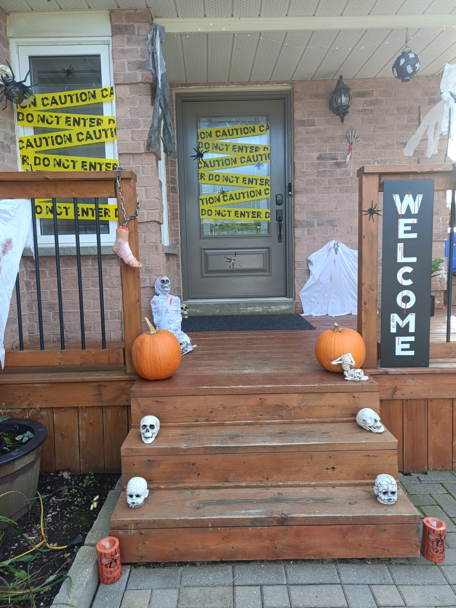 Real Halloween porch decoration setup by Komal Art Gallery with pumpkins, skulls, caution tape and hanging spooky decorations
