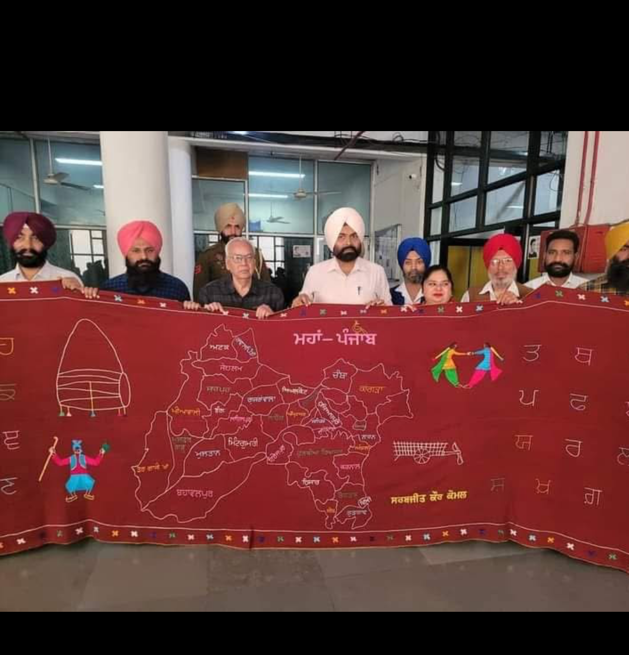 Sarabjit Kaur Komal presenting part of her large hand-embroidered Phulkari showing an old map of Punjab and Punjabi cultural motifs