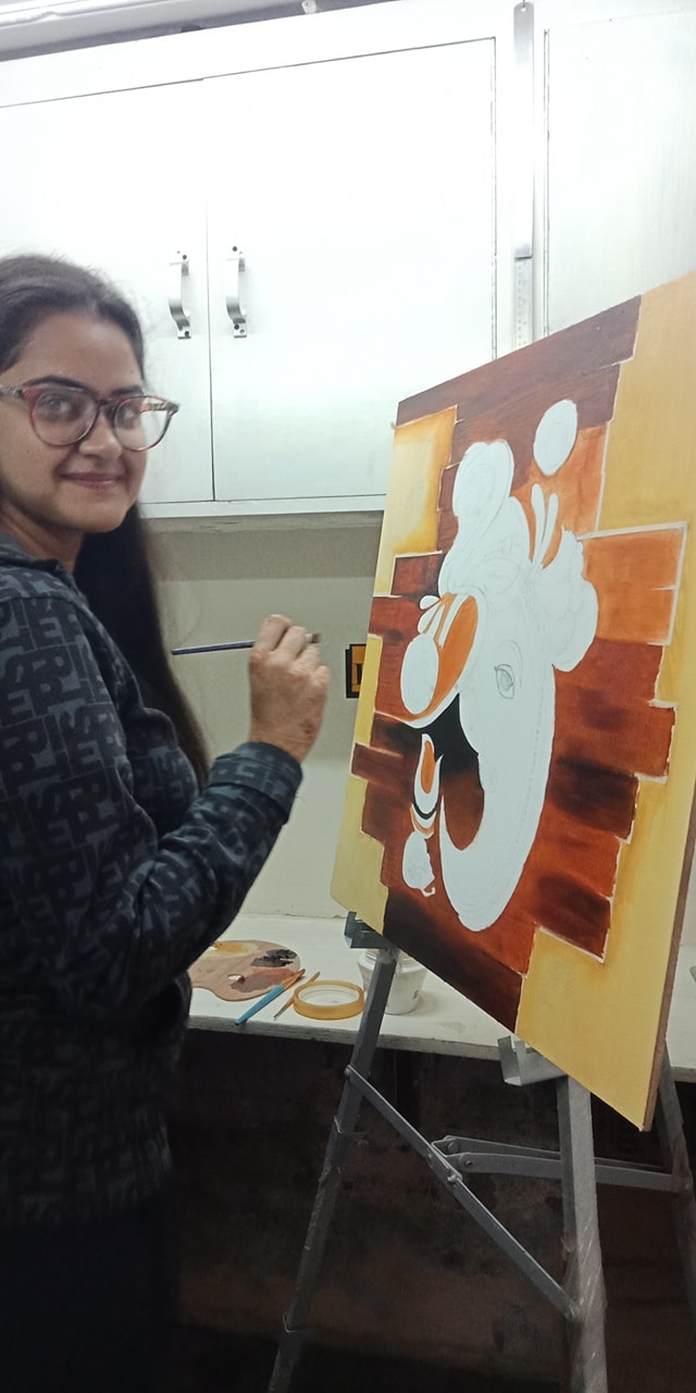 Student standing beside a painting in progress